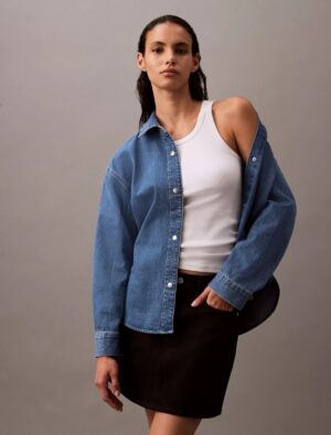 Woman wearing a calvin klein Relaxed Denim Button-Down Shirt and standing to prominent the CK shirts.