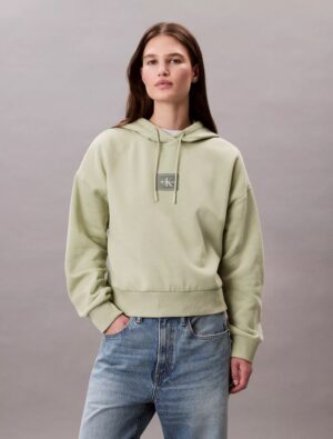 Front view of calvin klien Fleece Logo Patch Cropped Hoodie wearing by a women and standing in front of clean background.