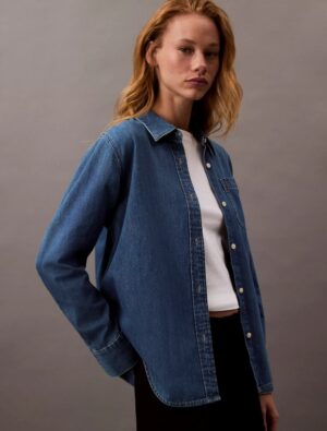 Woman wearing a calvin klein Classic Denim Shirt and standing to prominent the CK shirts.